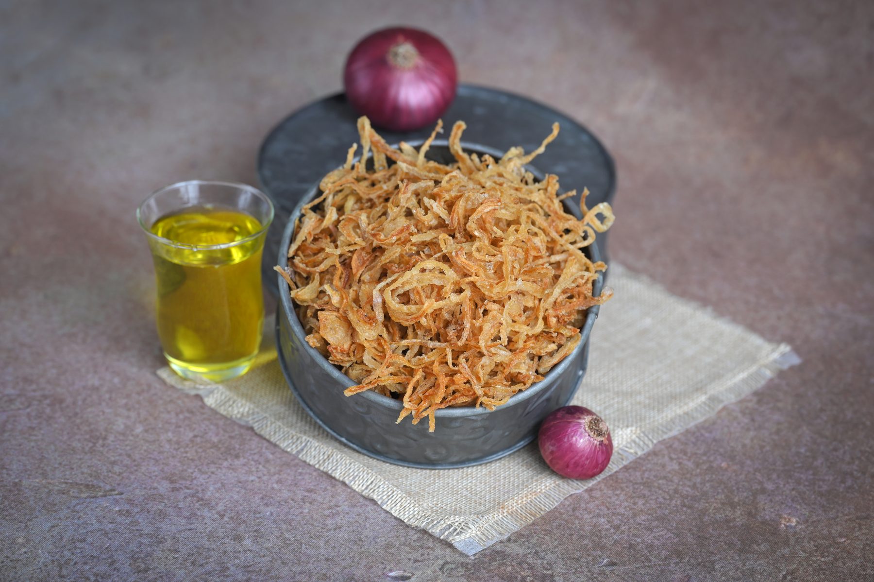 Fried onion flakes in bowl with onion and oil